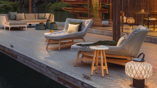 die_mbrace_sonnenliegen_von_dedon_sowie_weitere_loungemoebel_und_dekorative_lampen_von_dedon_auf_einer_holzterrasse_direkt_an_einem_see_erhaeltlich_im_onlineshop_henrik-bosse.de