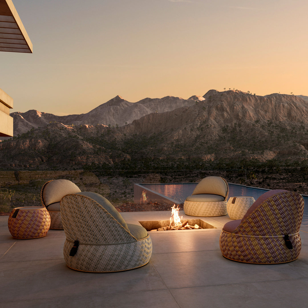 Vier DEDON DALA Lounge-Sessel in unterschiedlichen Farben rund um eine Feuerstelle auf einer Terrasse mit Bergpanorama