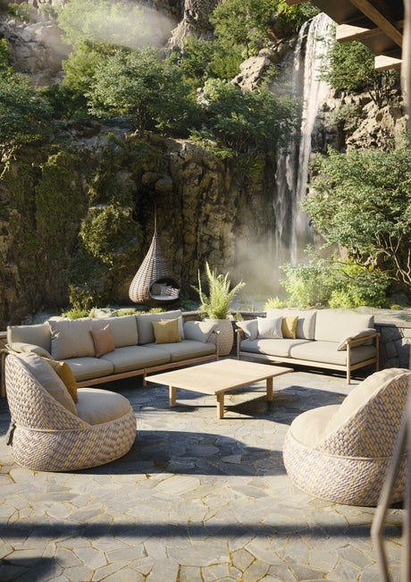Outdoor-Sitzlandschaft mit DEDON DALA Sesseln und Sofa-Gruppe auf Natursteinboden vor einem Wasserfall